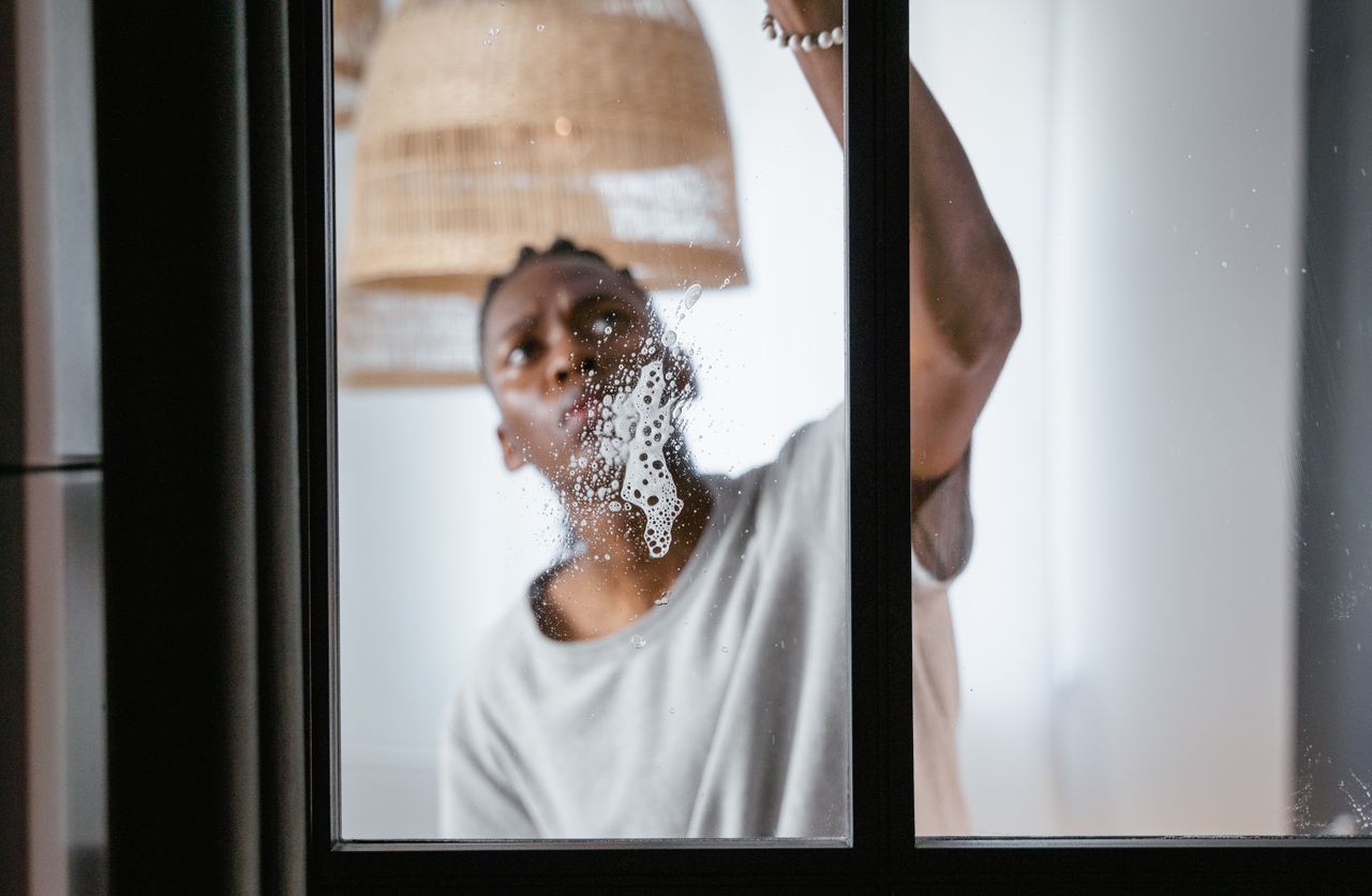 Mastering the First Impression: Your intriguing post title goes here An adult male cleaning a glass window indoors, focusing on household chores and cleanliness.